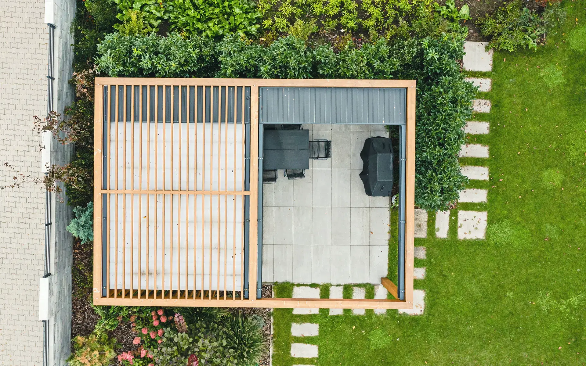 Nowoczesna pergola ogrodowa drewniana na płytach betonowych. Ażurowe zadaszenie.