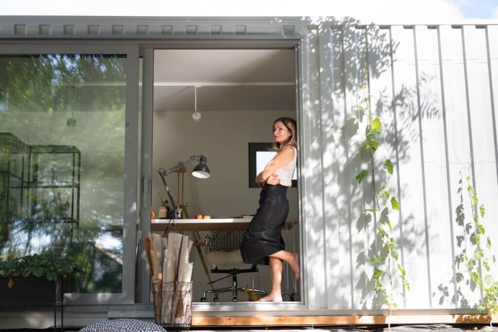 Biuro w ogrodzie w kontenerze. Kobieta stojąca przy wejściu.